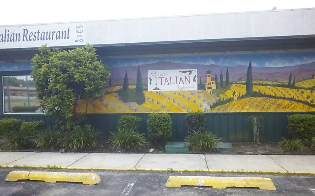 Façade de Mama’s Italian Restaurant ornée d’une longue fresque représentant un paysage toscan.
