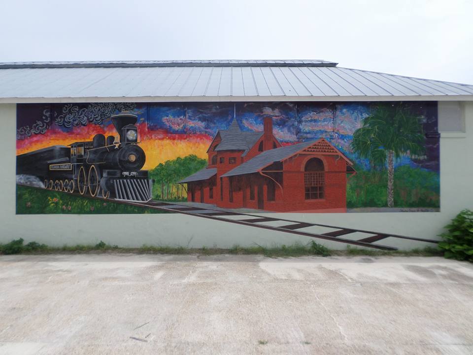 Fresque du Perry City Hall représentant une locomotive noire, une gare rouge et un paysage arboré.
